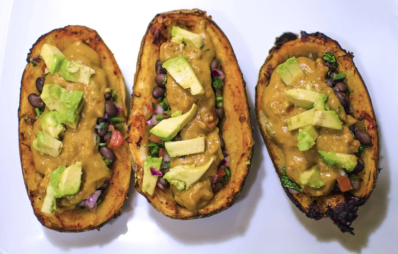 A group of delicious potato skins, with sauce, beans, and avocado
